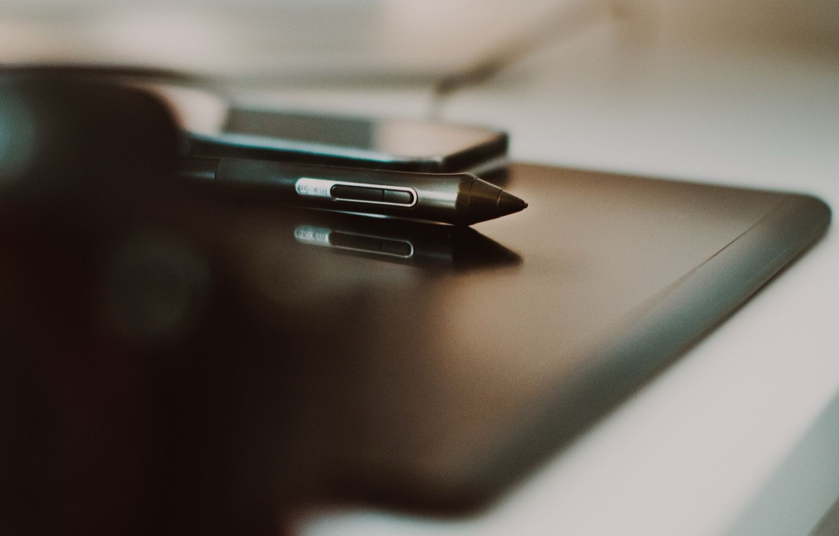 A close-up of a stylus pen drawing on a tablet screen for freelance design work.