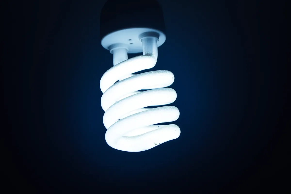 Close-up of a glowing spiral energy-saving bulb against a dark backdrop, emphasizing sustainable energy.