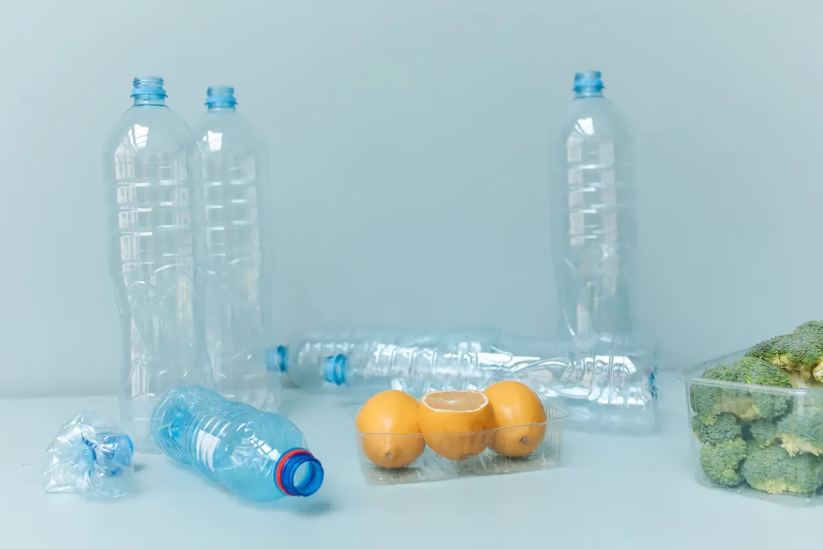 A conceptual photo of plastic bottles, lemons, and broccoli illustrating waste and sustainability.